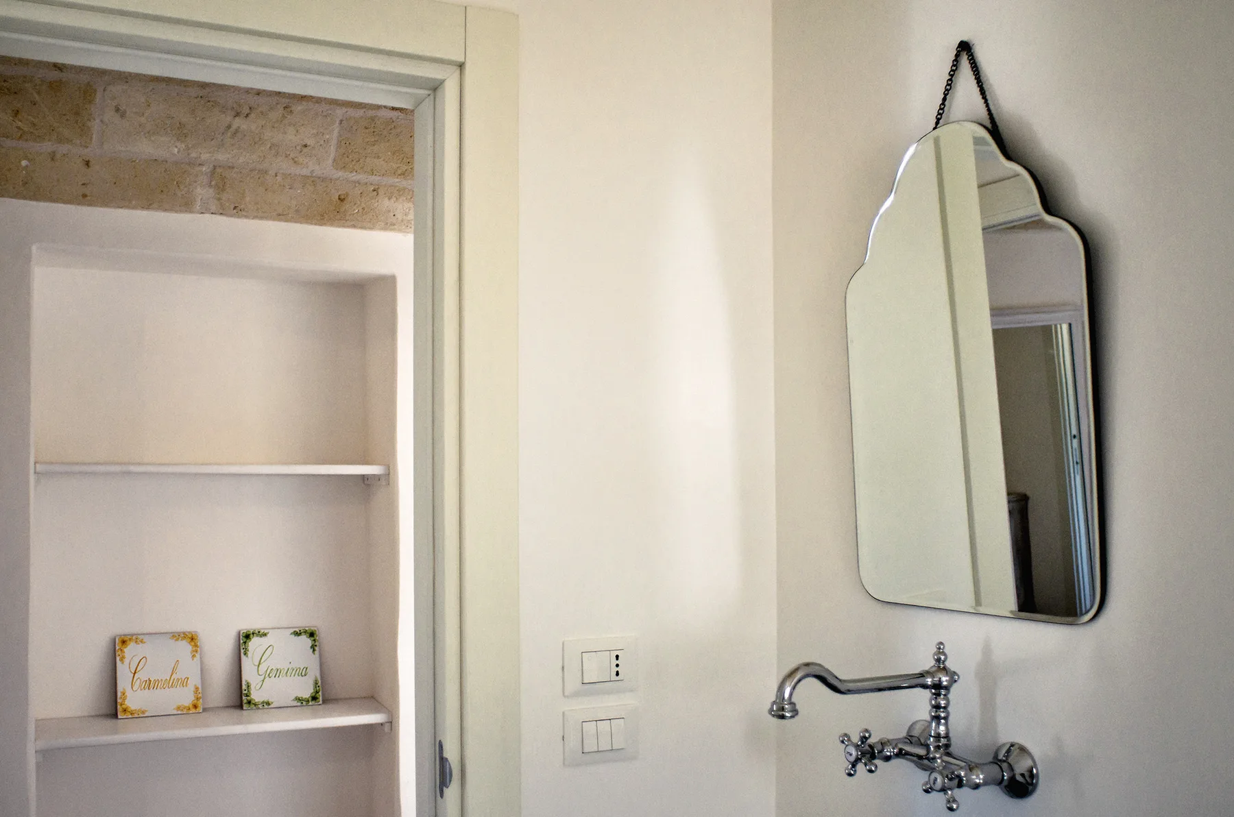 Un lavabo de baño con espejo de pared y estantes abiertos.