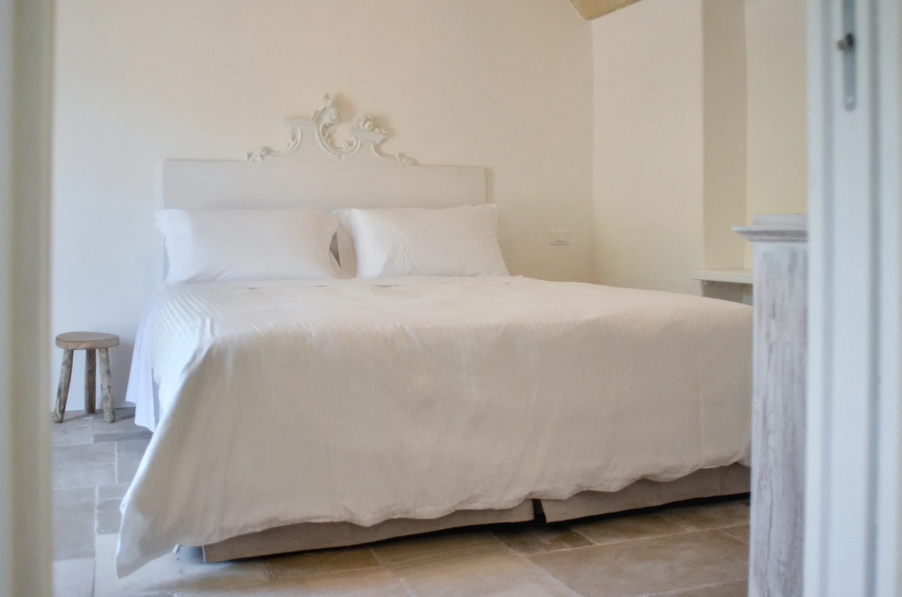 Un dormitorio con una cama bien tendida y ropa de cama clara.