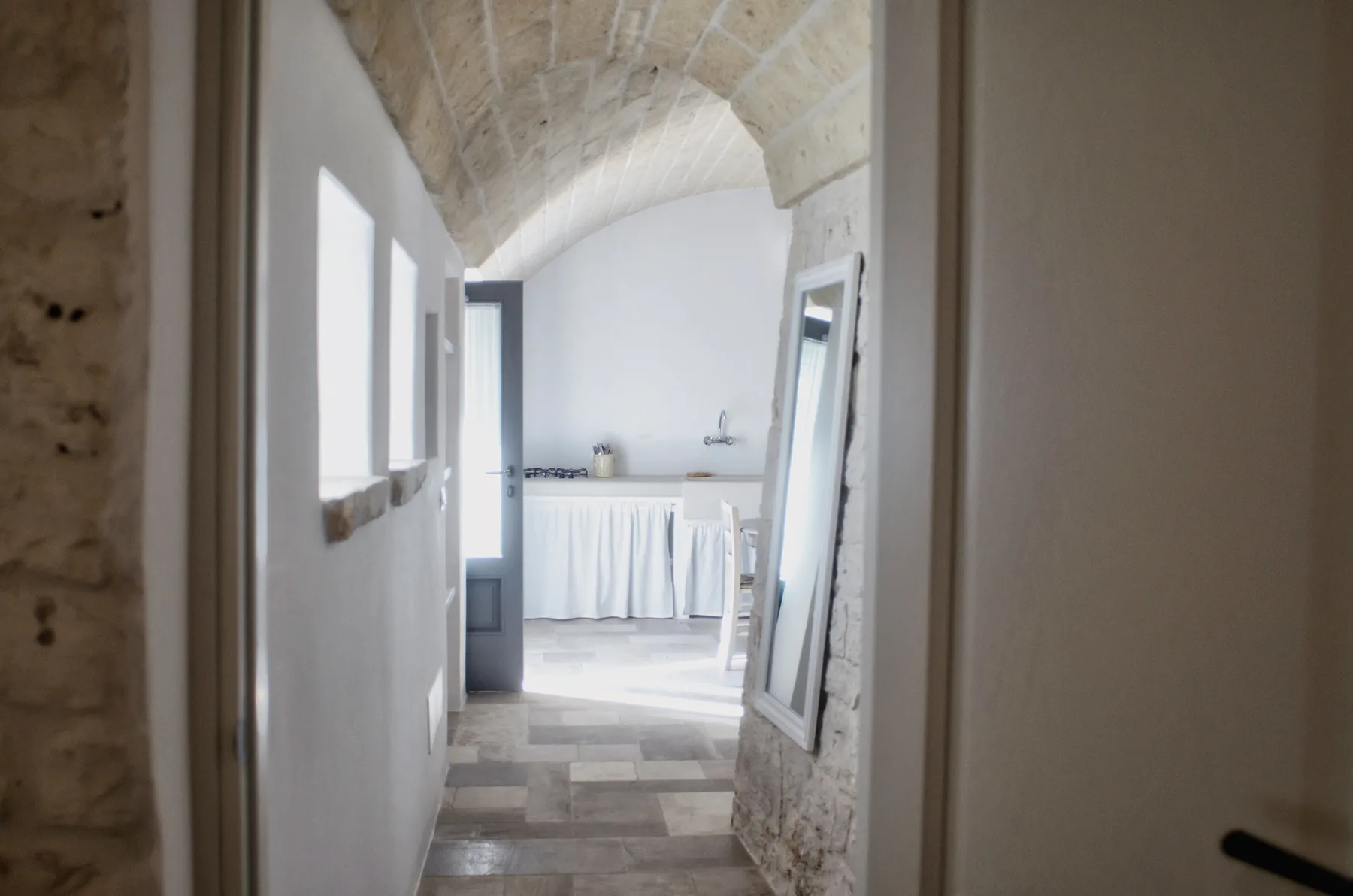 Un baño luminoso con techo abovedado de piedra y un lavabo bajo una encimera con cortina.