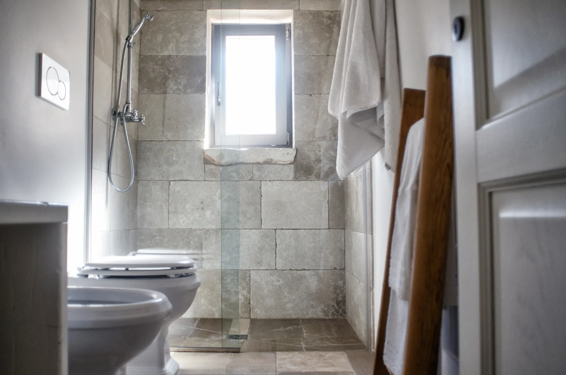 Un baño con azulejos, ducha, inodoro y una ventana pequeña.