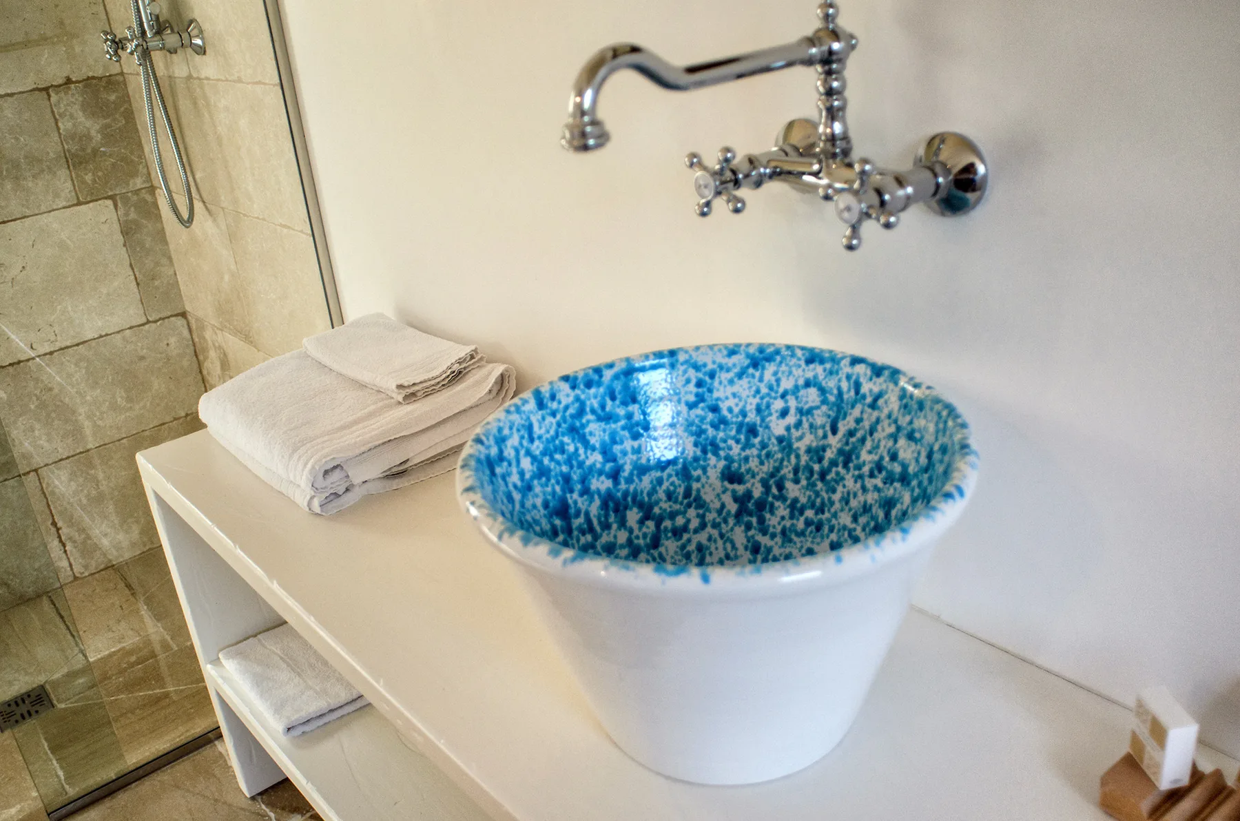 Un lavabo de baño con un cuenco azul estampado y toallas dobladas.