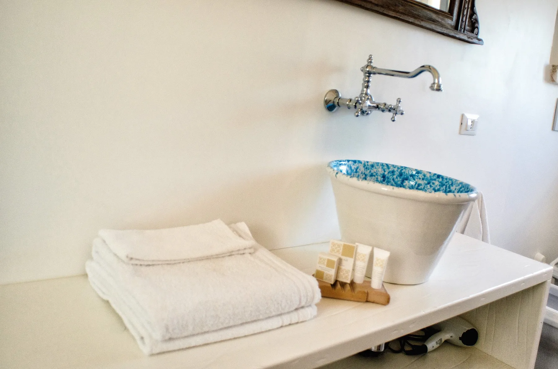 Un tocador de baño con toallas dobladas y un lavabo de borde azul.