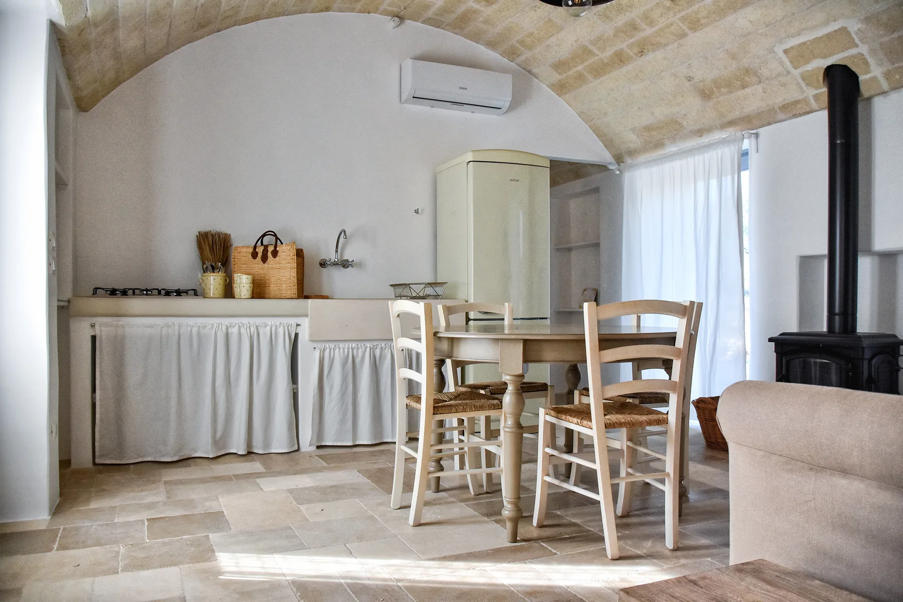 Una cocina rústica y zona de comedor con mesa, asientos y estufa.