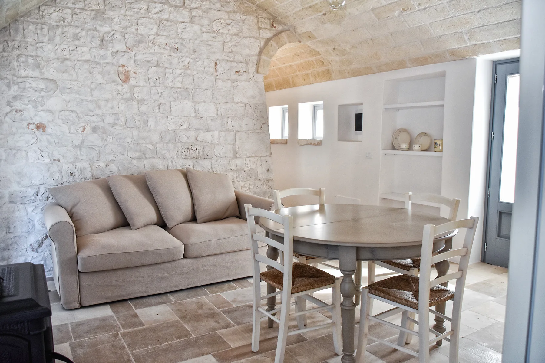 Una sala de estar y comedor con paredes de piedra y asientos alrededor de una mesa.