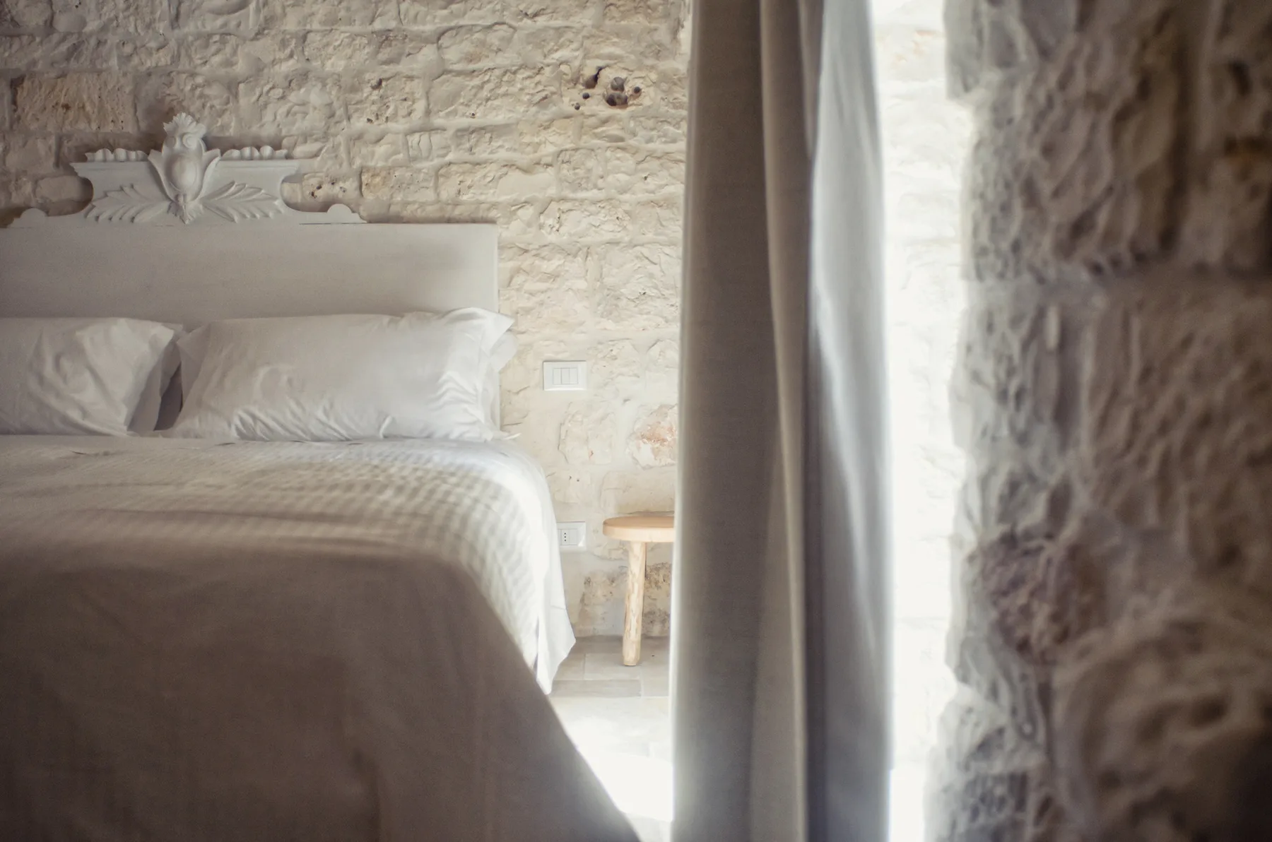 Un dormitorio con una cama bien arreglada junto a una ventana luminosa.