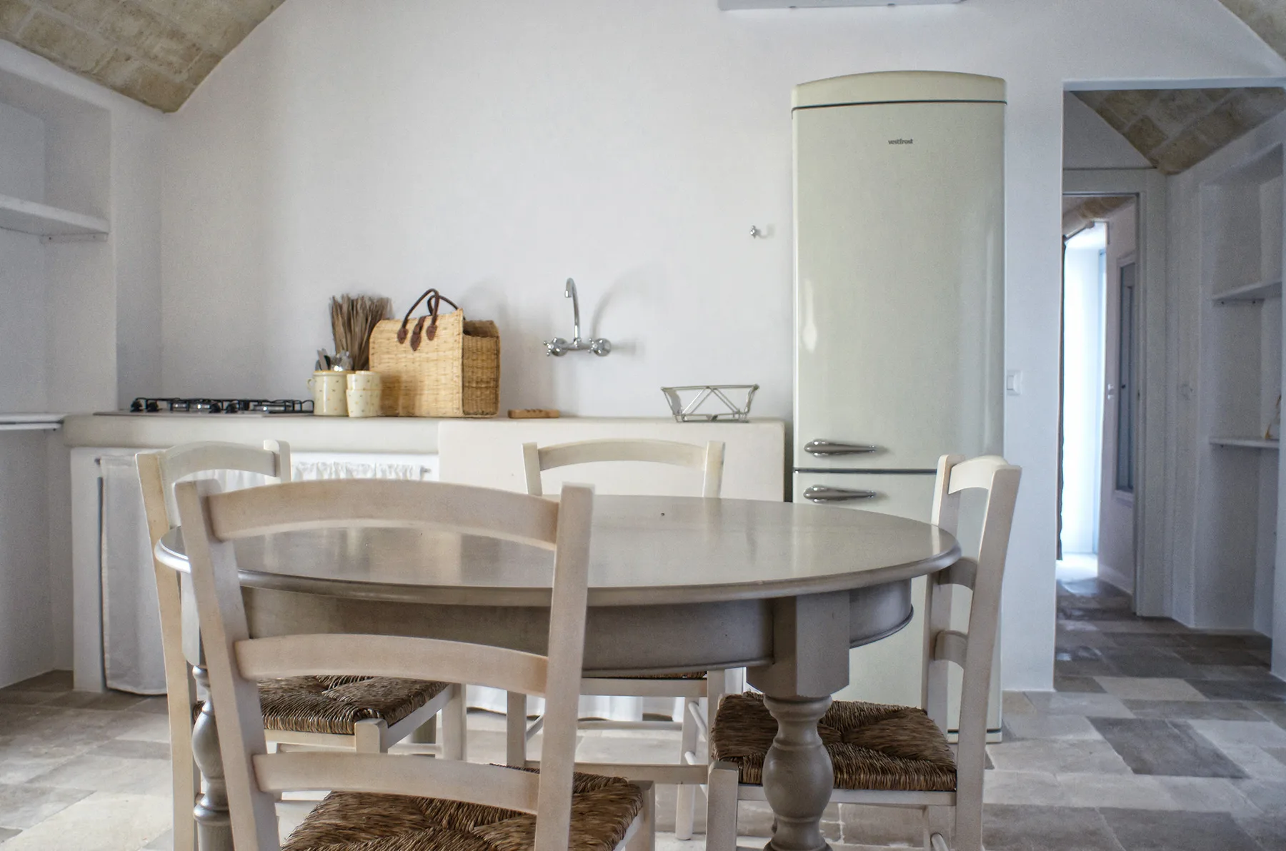 Una cocina luminosa con zona de comedor, mesa redonda y armarios blancos.