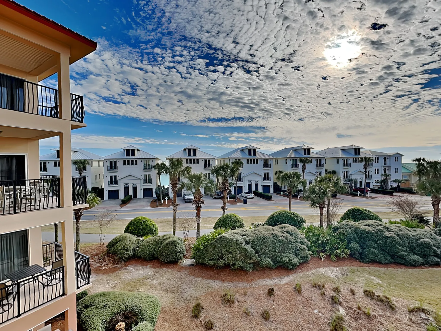 A landscaped residential complex with apartment buildings beneath a partly cloudy sky.