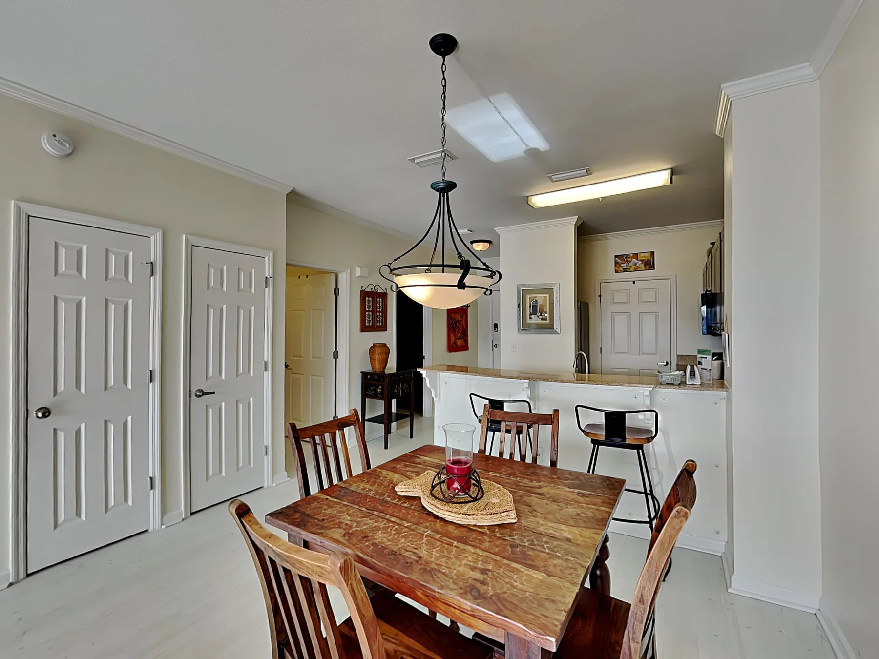 A dining area with a wooden table and chairs beneath a hanging light.
