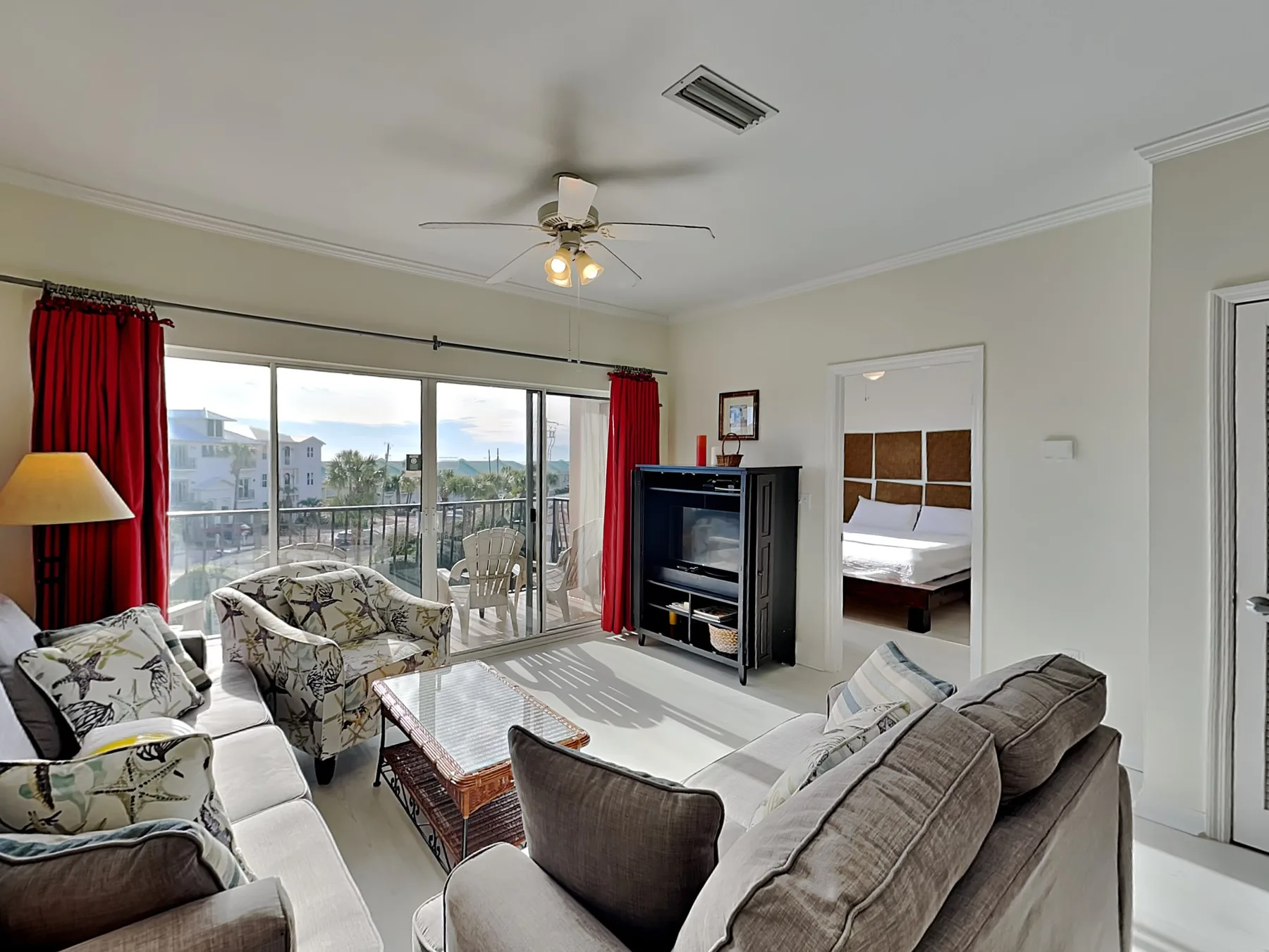 A living room with seating, a television, and sliding glass doors opening to a balcony.