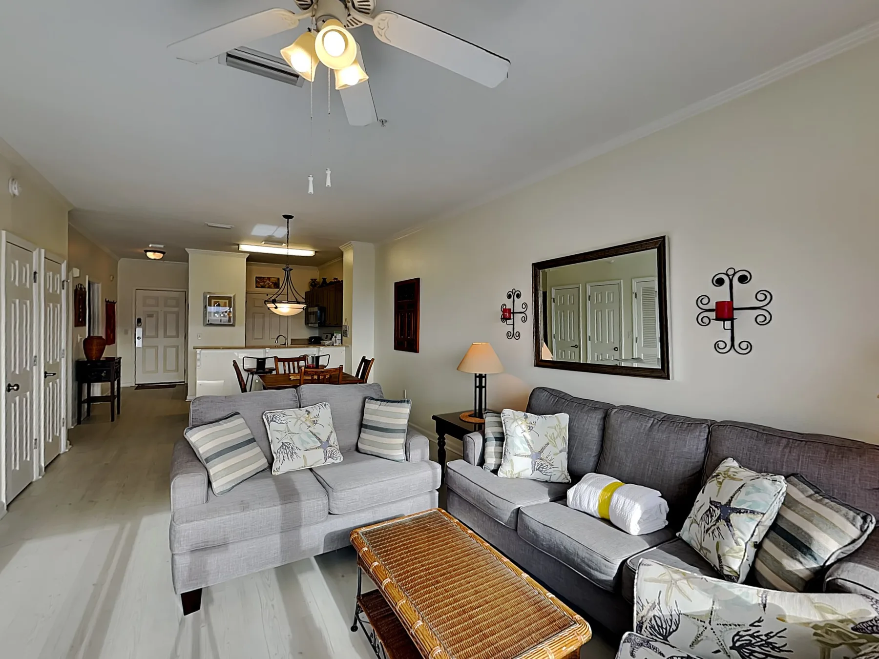 A living room with gray seating, a woven coffee table, and a ceiling fan.
