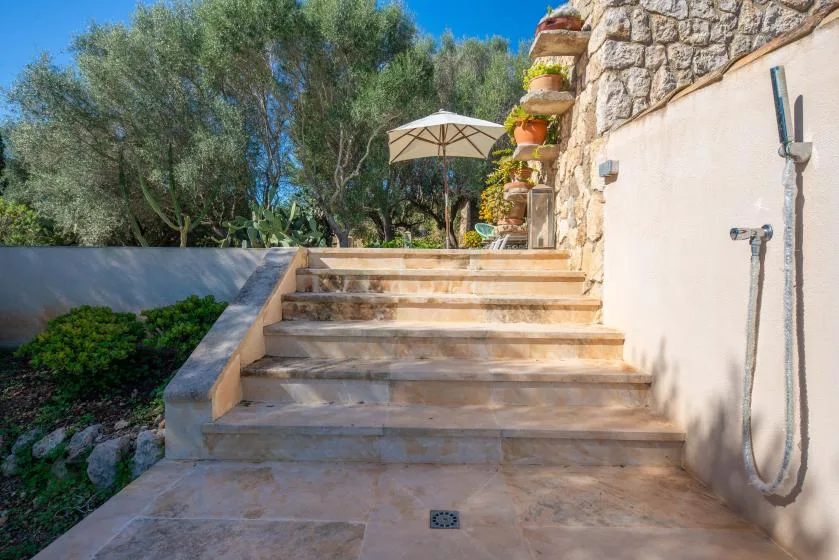 Outdoor stone steps lead up to a garden patio with an umbrella.
