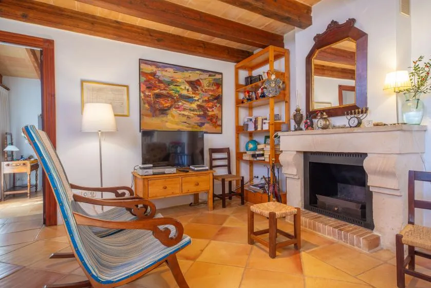 A living room with a television, wooden seating, and a fireplace.