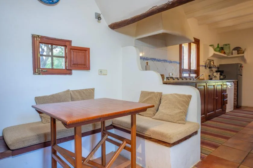 A dining table and built-in seating sit beside a compact kitchen.