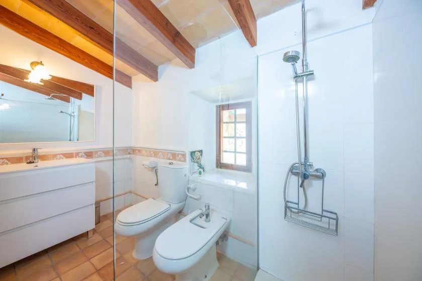 A bright bathroom with a shower, toilet, and white sink cabinet.