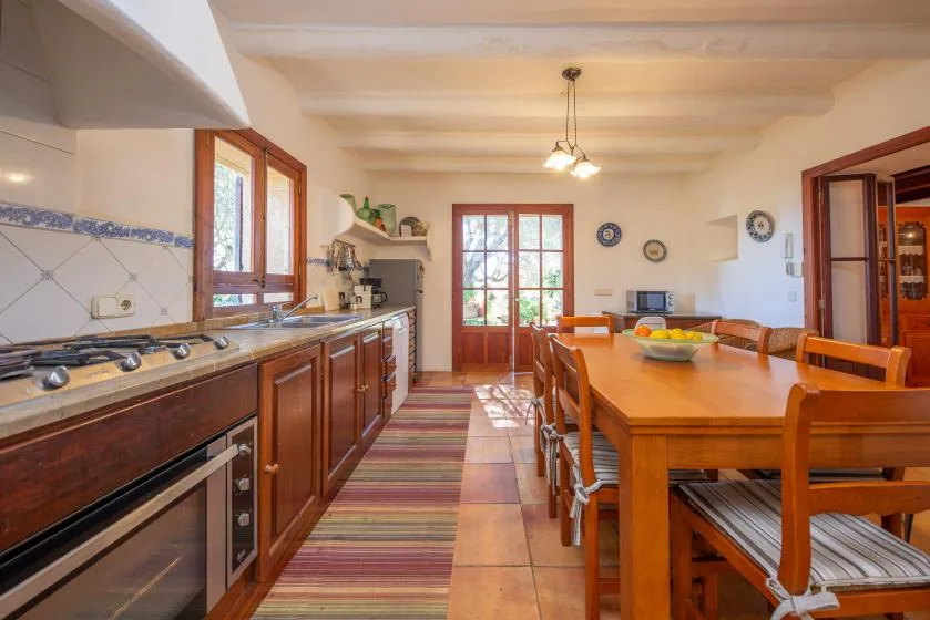A dining room with a long wooden table beside a kitchen counter.