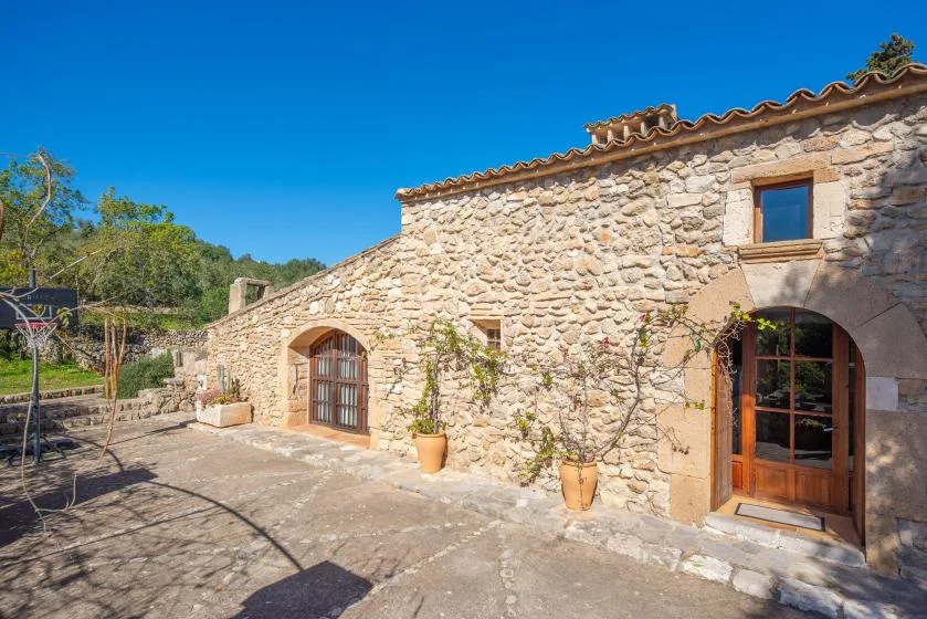 A stone house exterior with arched wooden doors and a paved courtyard.