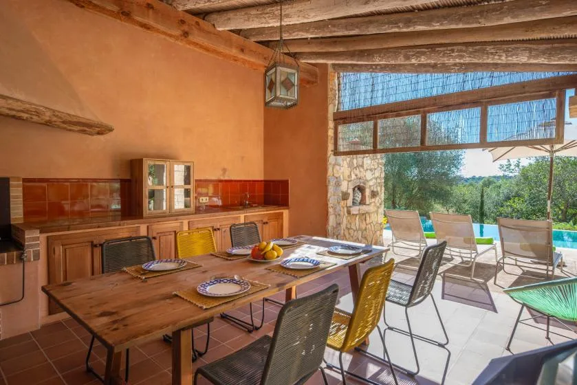 A rustic dining area opens onto a patio with outdoor seating and greenery.