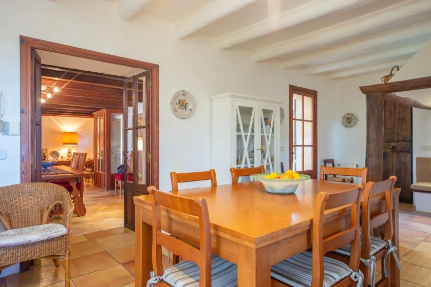 A dining room with a wooden table and chairs beside an open doorway.