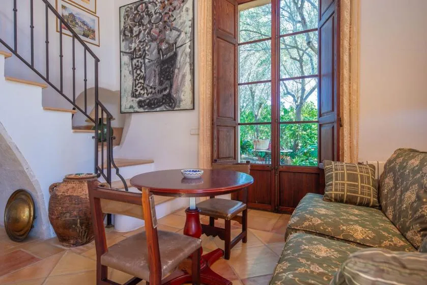 A sitting area with a round table beside a tall window and staircase.