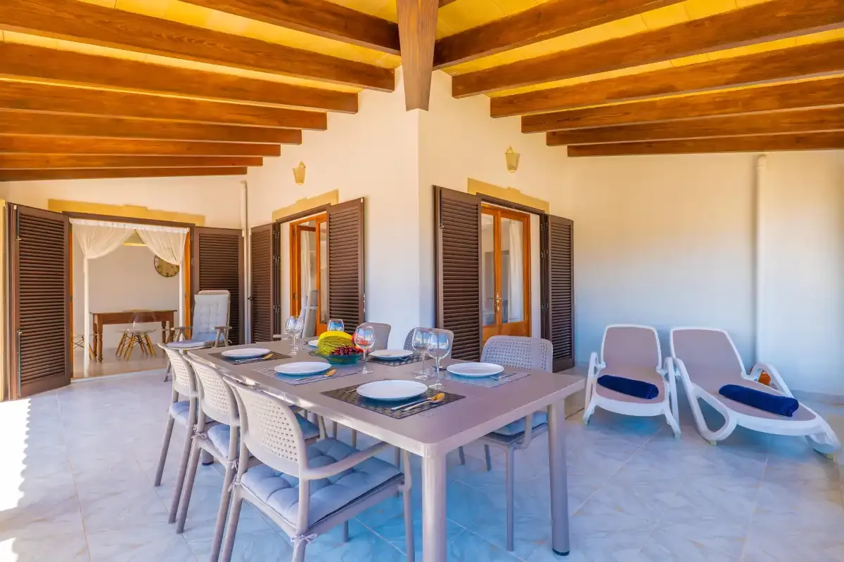 A dining area with a set table and chairs beneath exposed wooden beams.