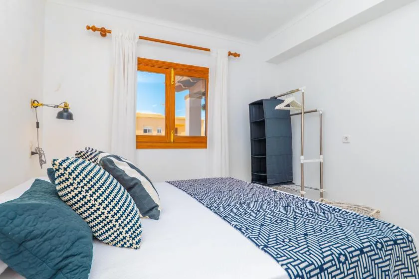 A bedroom with a bed, patterned bedding, and a window with curtains.
