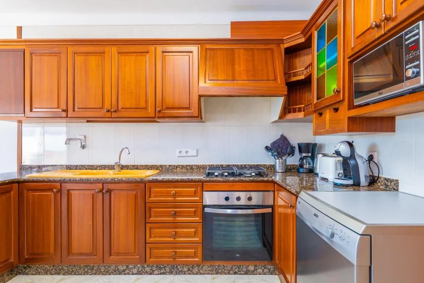 A kitchen with wooden cabinets, a countertop, and cooking appliances.