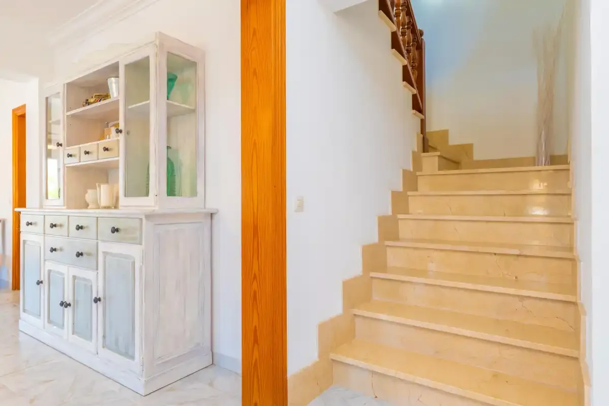 A bright interior hallway with a built-in cabinet beside a staircase.