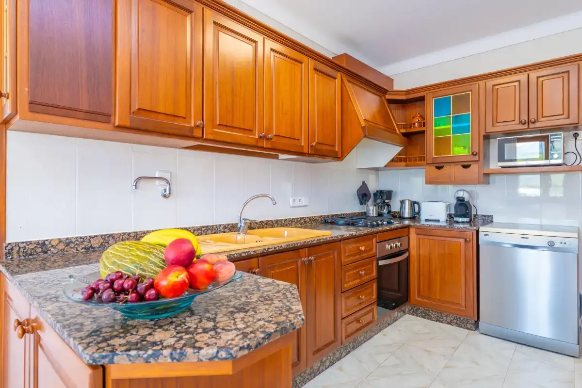 A kitchen with wooden cabinets and a fruit bowl on the counter.