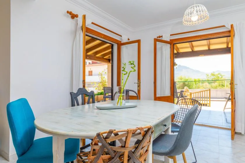 A dining area with a large table and open doors leading to a terrace.