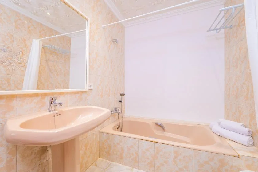 A bathroom with a bathtub, sink, and large wall mirror.