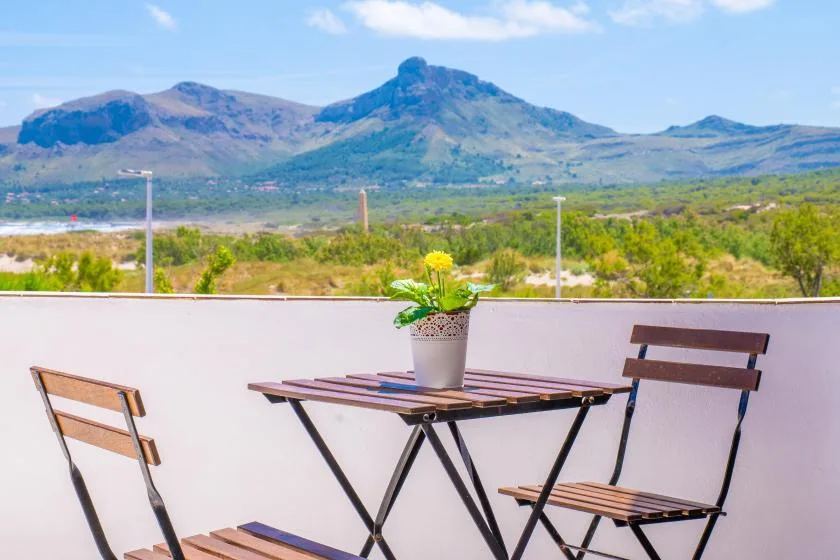 An outdoor patio table and seating overlook a green valley and distant mountains.
