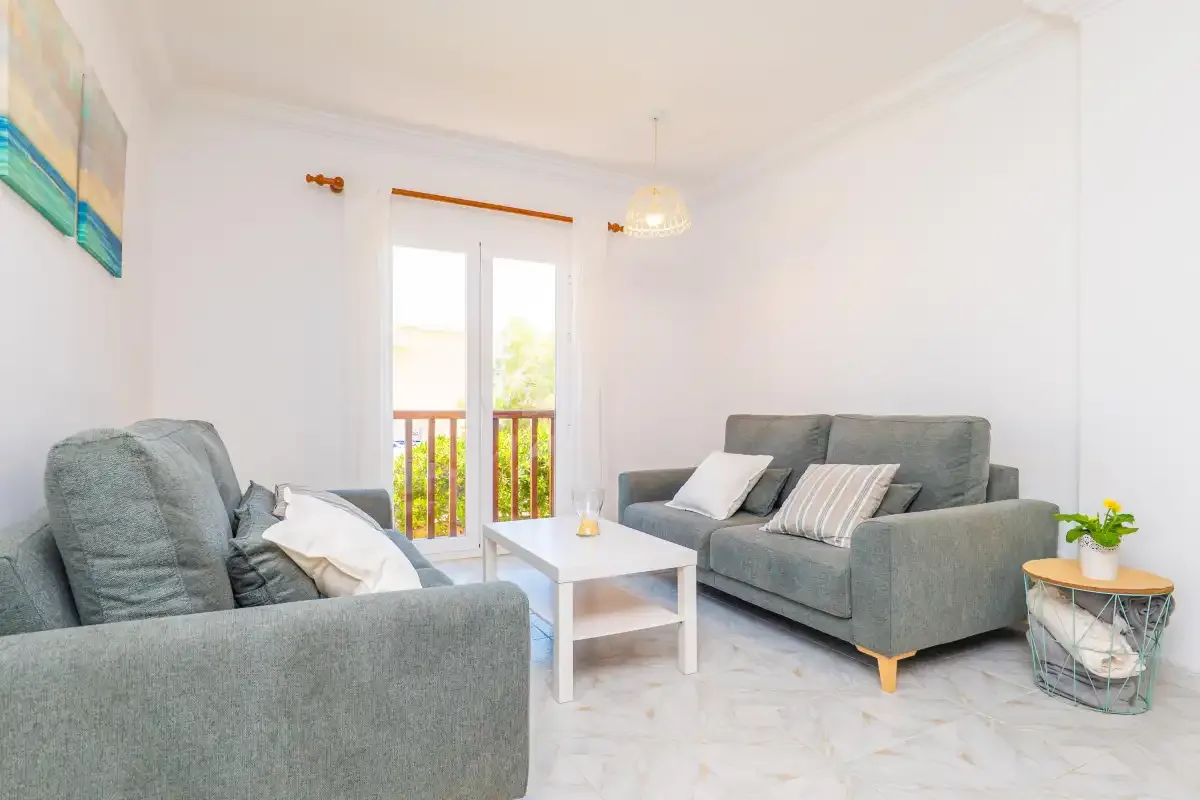 A bright living room with gray seating around a white coffee table.