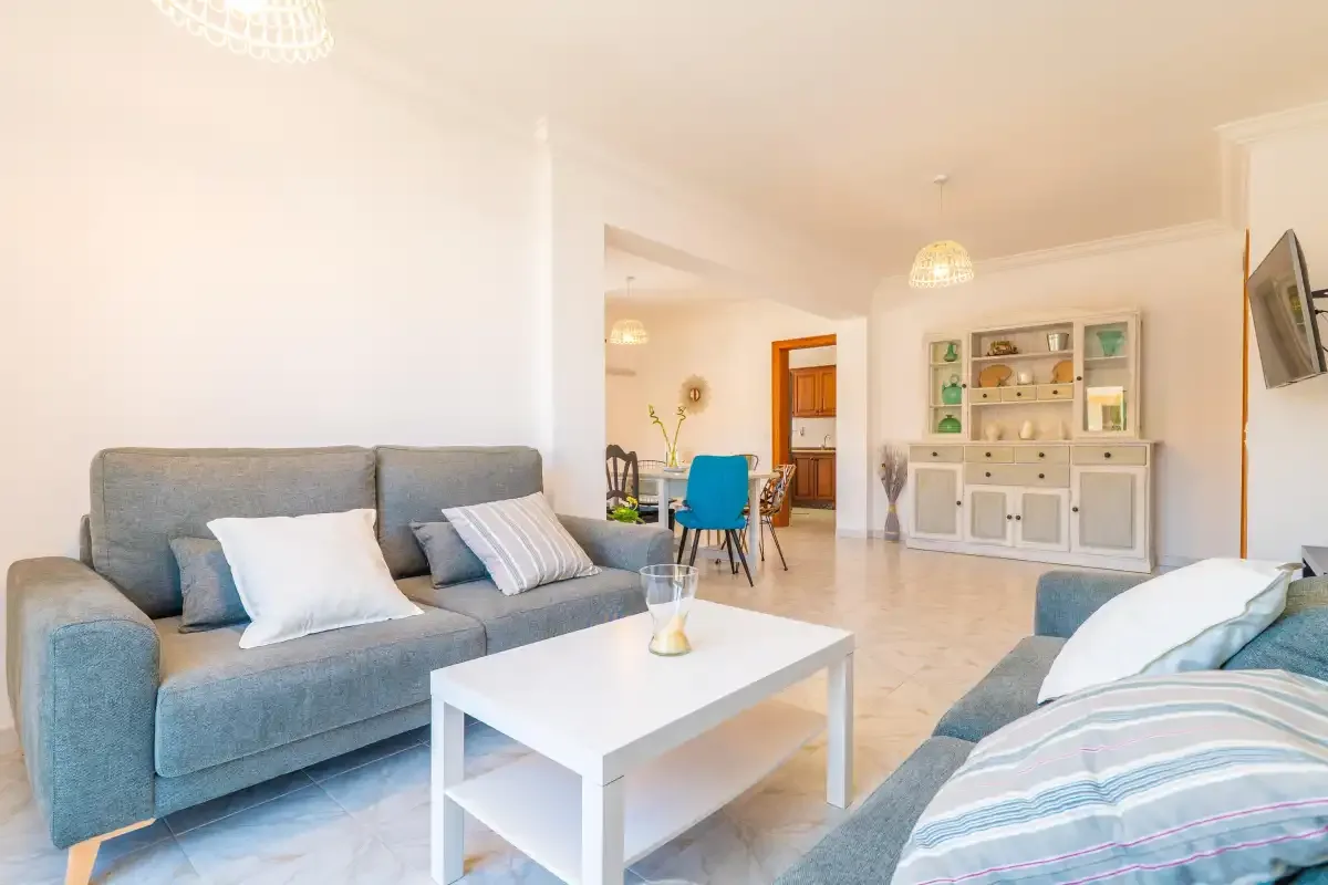 A bright living room with seating, a coffee table, and a dining area.