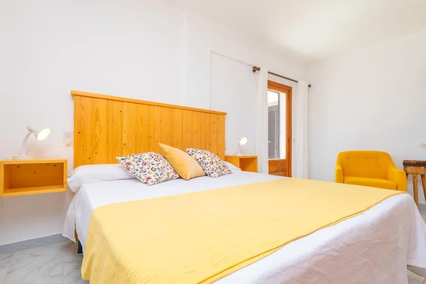 A bedroom with a bed covered in yellow bedding and a wooden headboard.