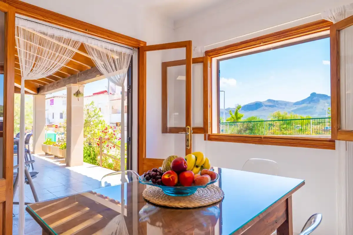 A dining area opens onto a bright patio, with mountain views through the window.