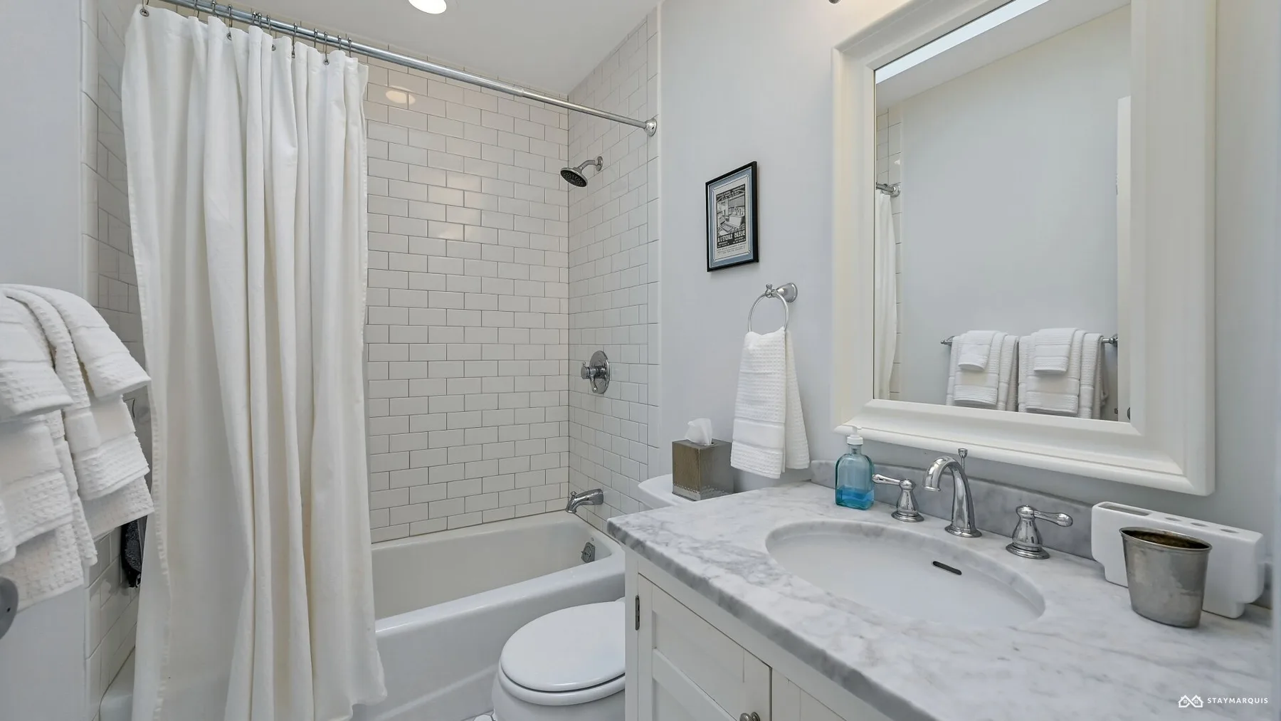 A bathroom with a bathtub, shower curtain, and sink beneath a large mirror.