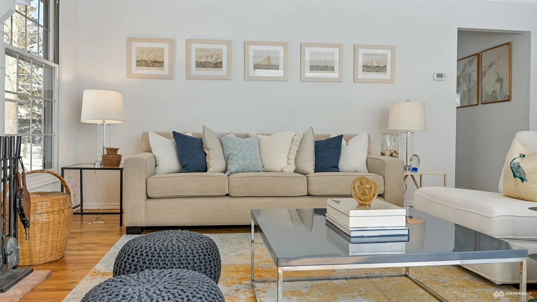 A bright living room with seating, framed artwork, and a glass coffee table.