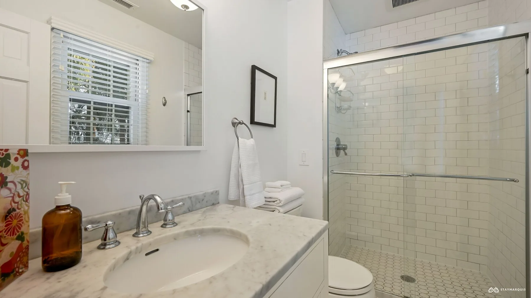 A bathroom with a sink vanity and glass-enclosed shower.