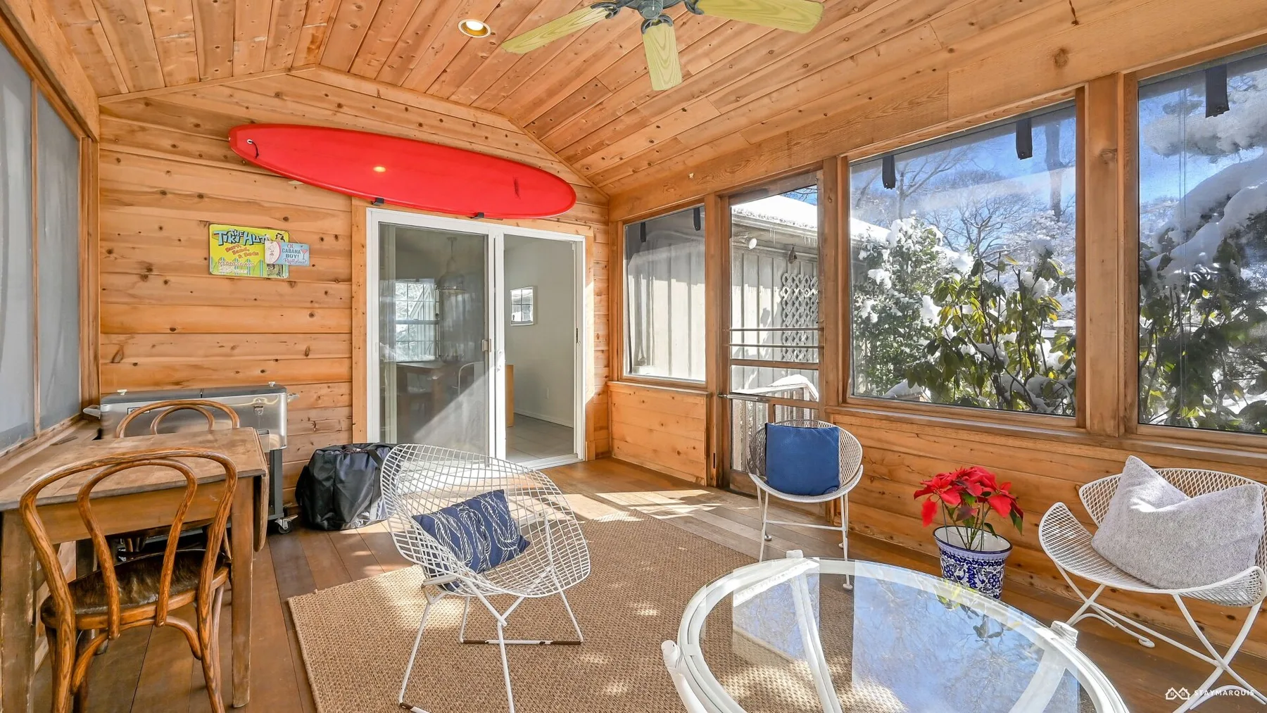 A sunroom with large windows, wicker seating, and a round glass table.