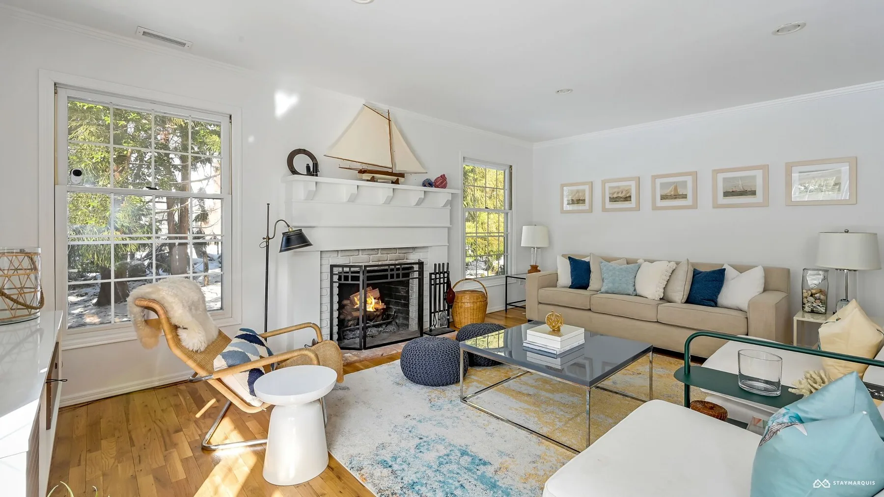 A bright living room with a fireplace, seating, and large windows.