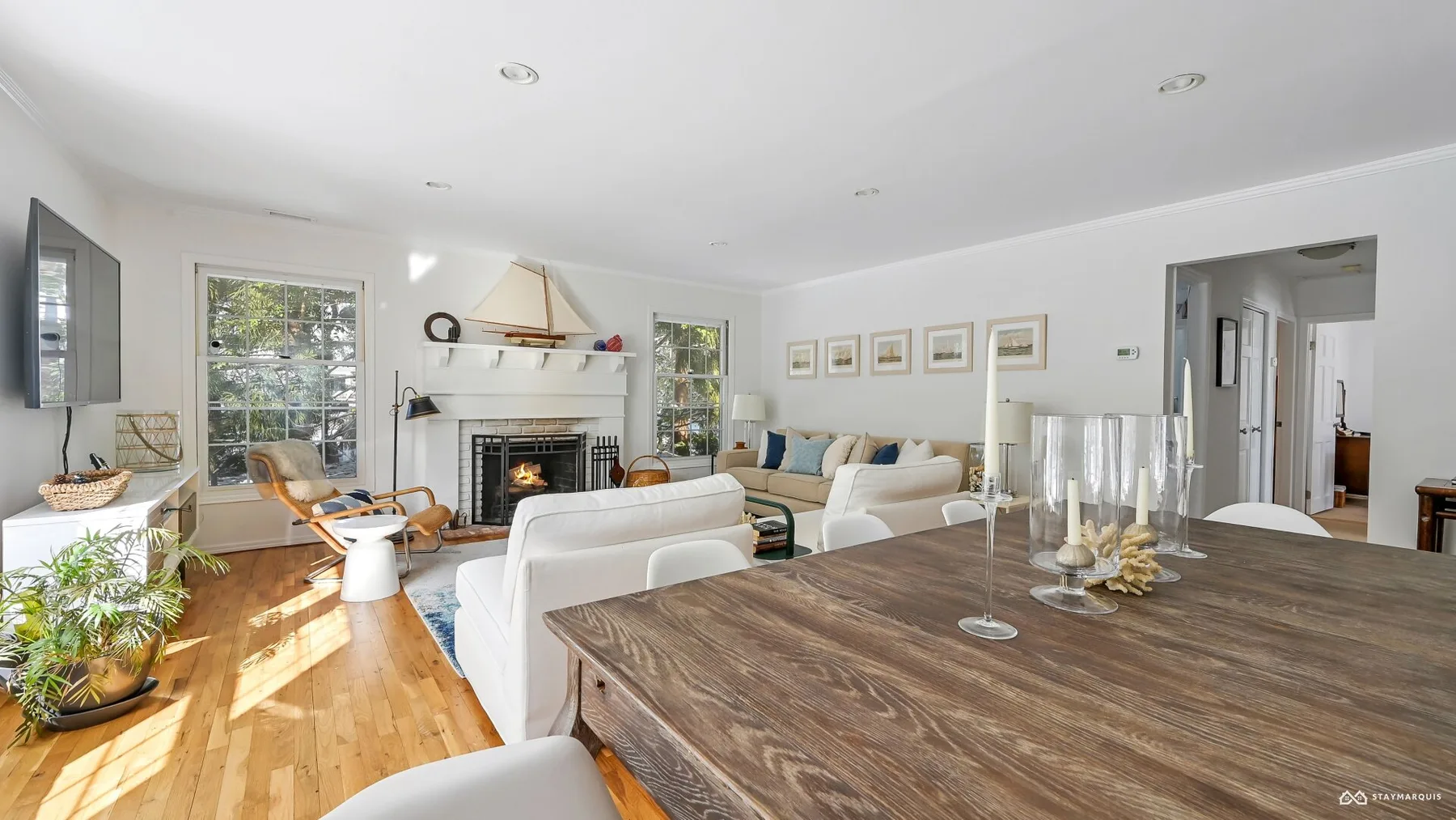 A bright living room with seating around a fireplace and a large dining table.