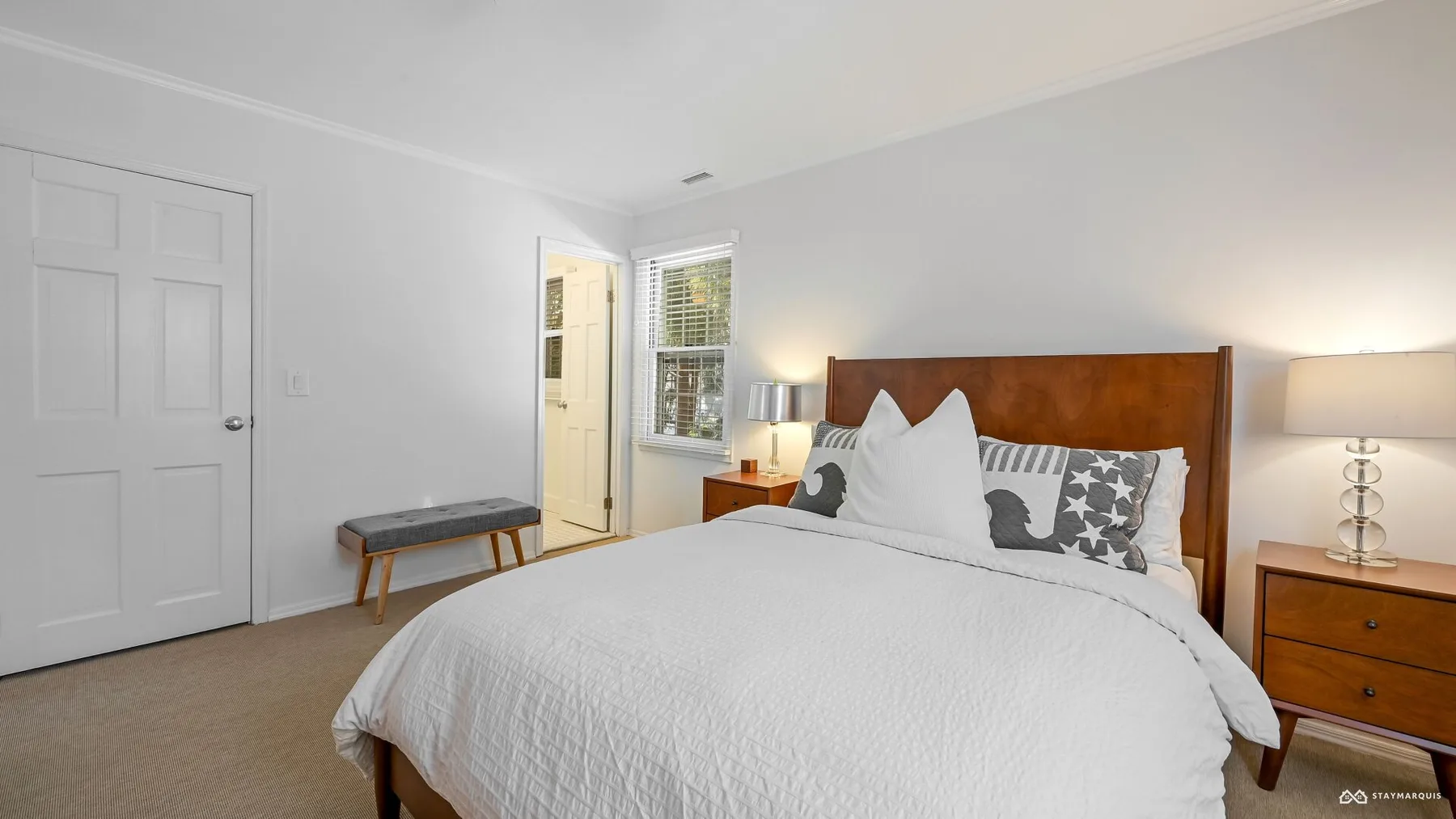 A bright bedroom with a neatly made bed and a wooden headboard.