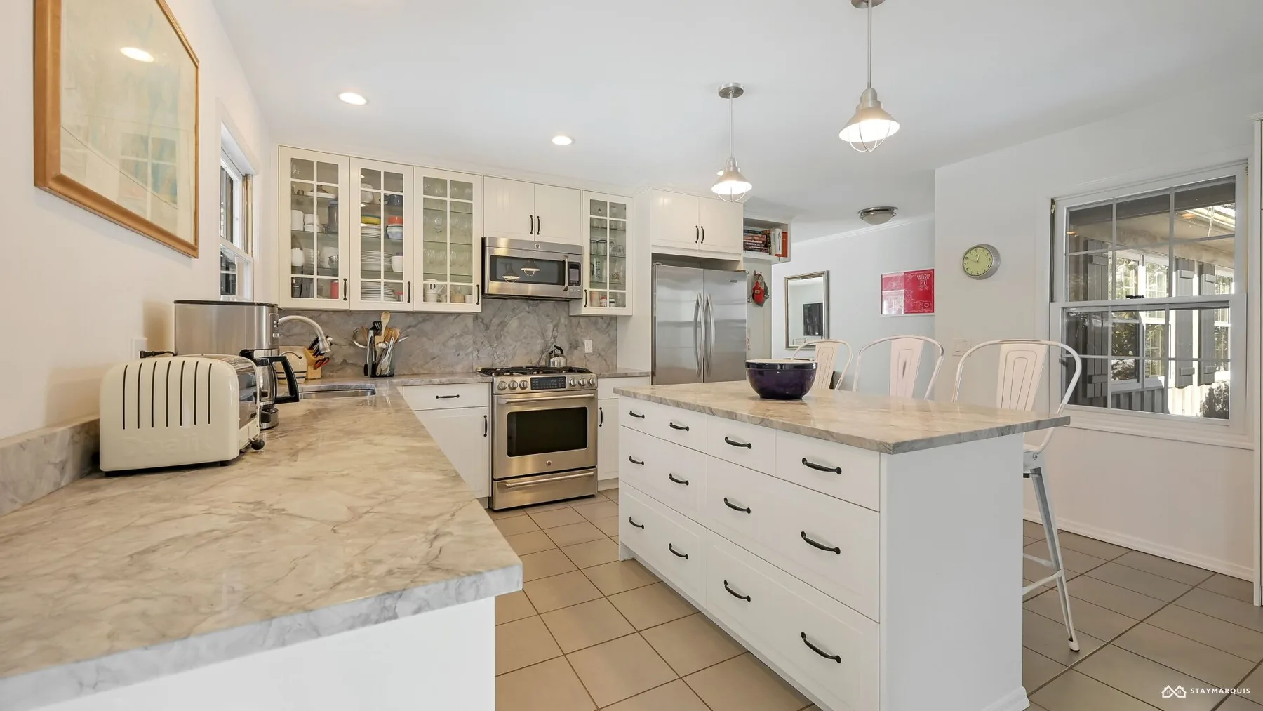 A bright kitchen with white cabinets and a central island.