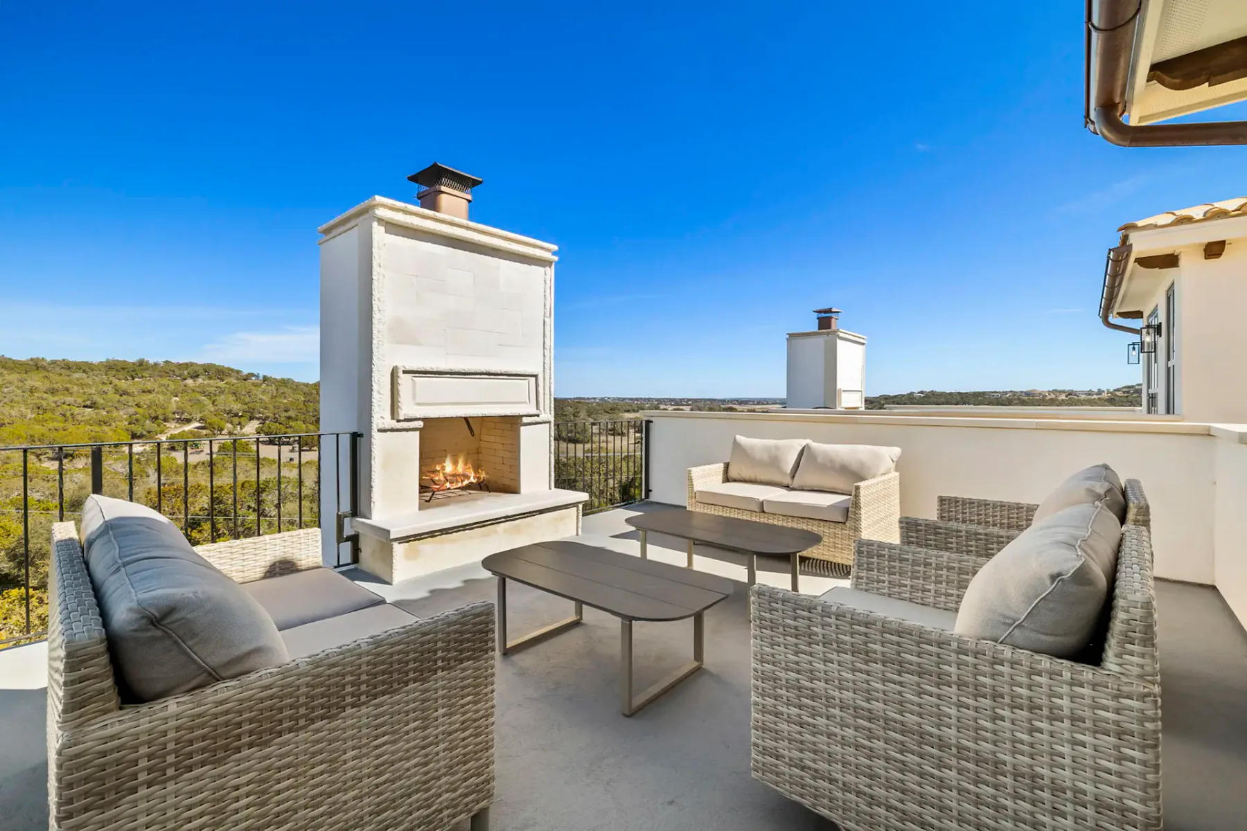 Patio en la azotea con asientos de mimbre y una chimenea con vistas al paisaje circundante.