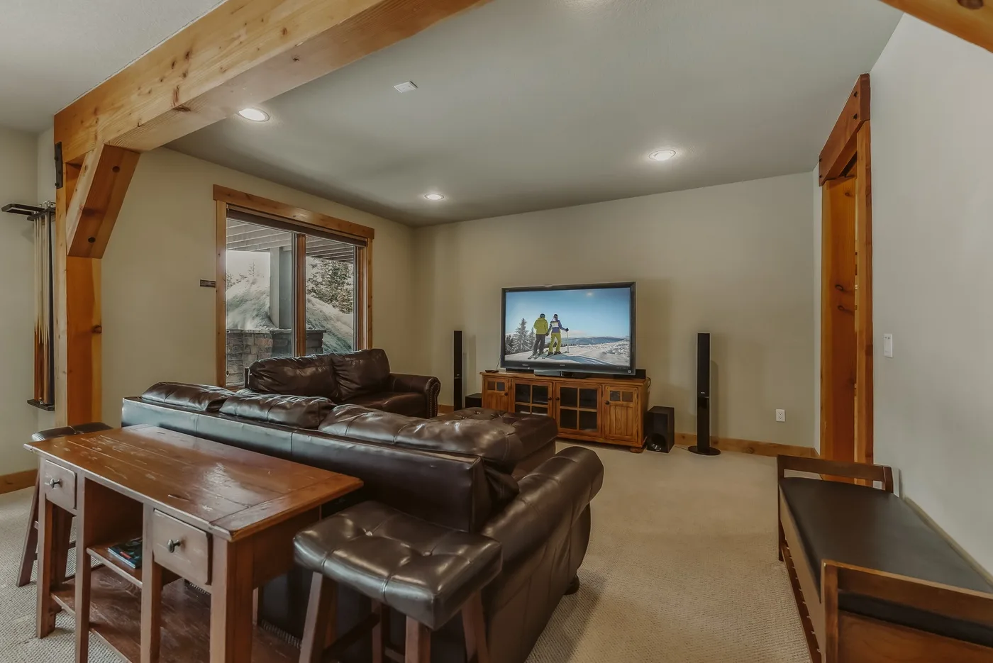 Una sala de estar con asientos de cuero, una mesa de centro de madera y un televisor.