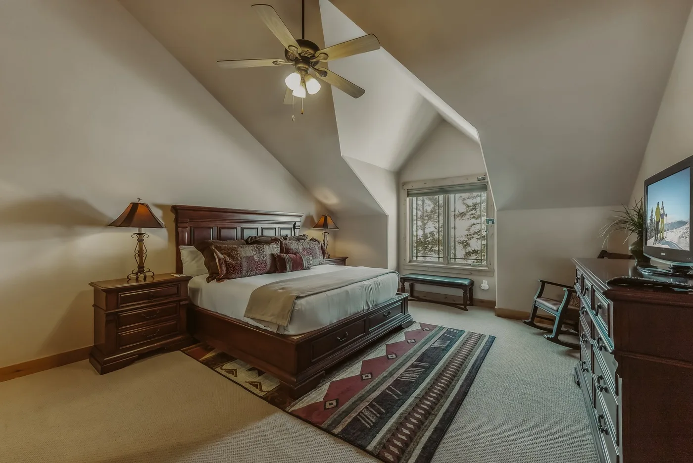 Un dormitorio amplio con una cama grande, una alfombra estampada y una ventana.