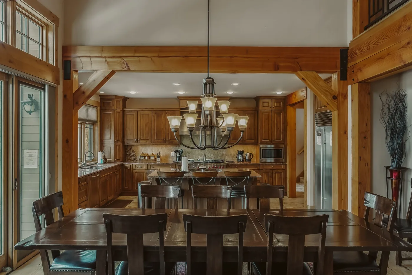 Un comedor con una mesa larga y asientos de madera frente a una cocina.