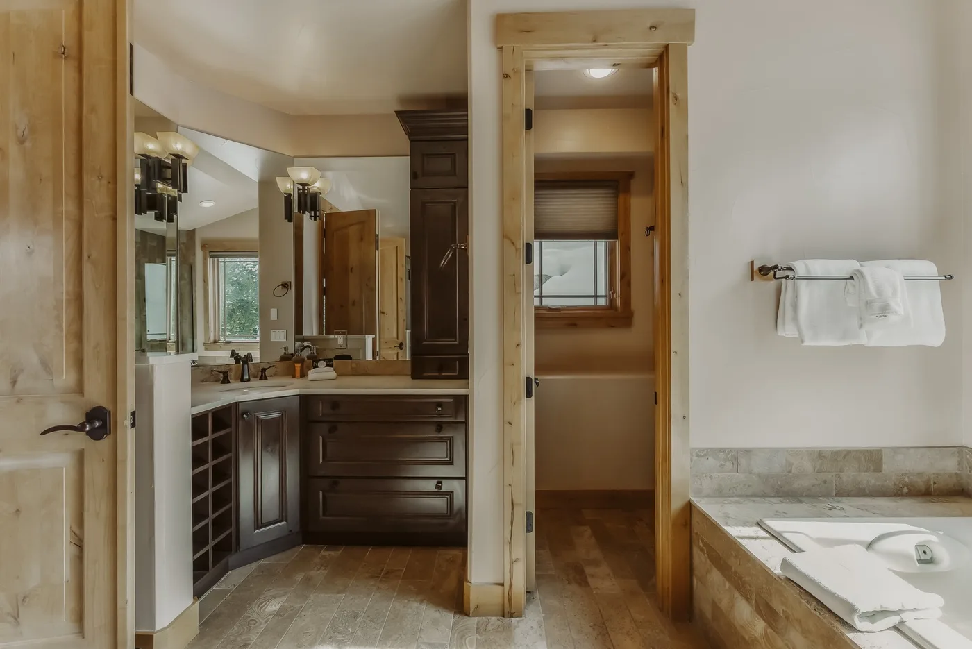 Un baño con tocador de dos lavabos, armarios de madera y bañera.