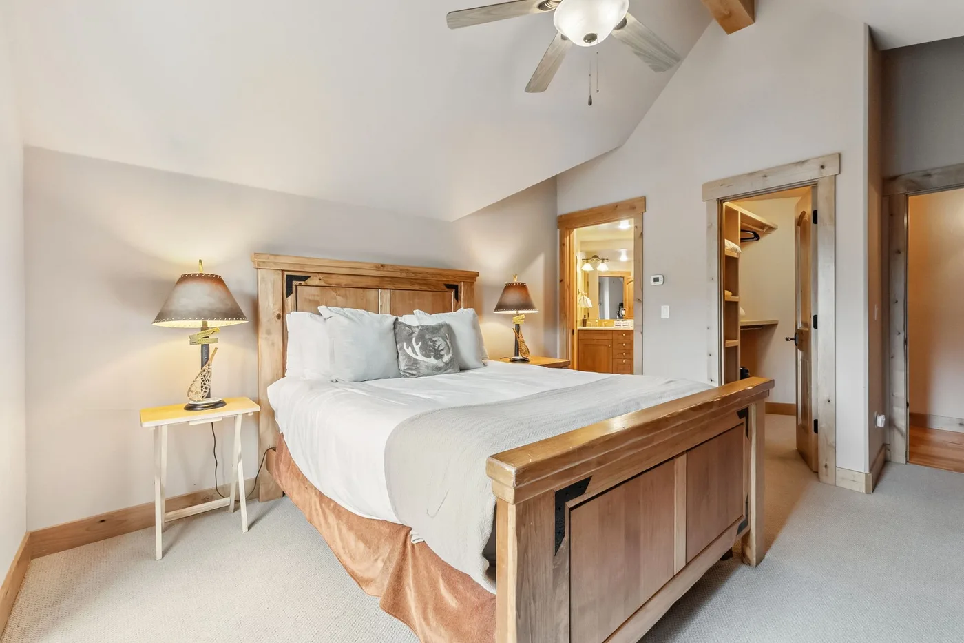 Un dormitorio con una cama de madera, ropa de cama blanca y un ventilador de techo.