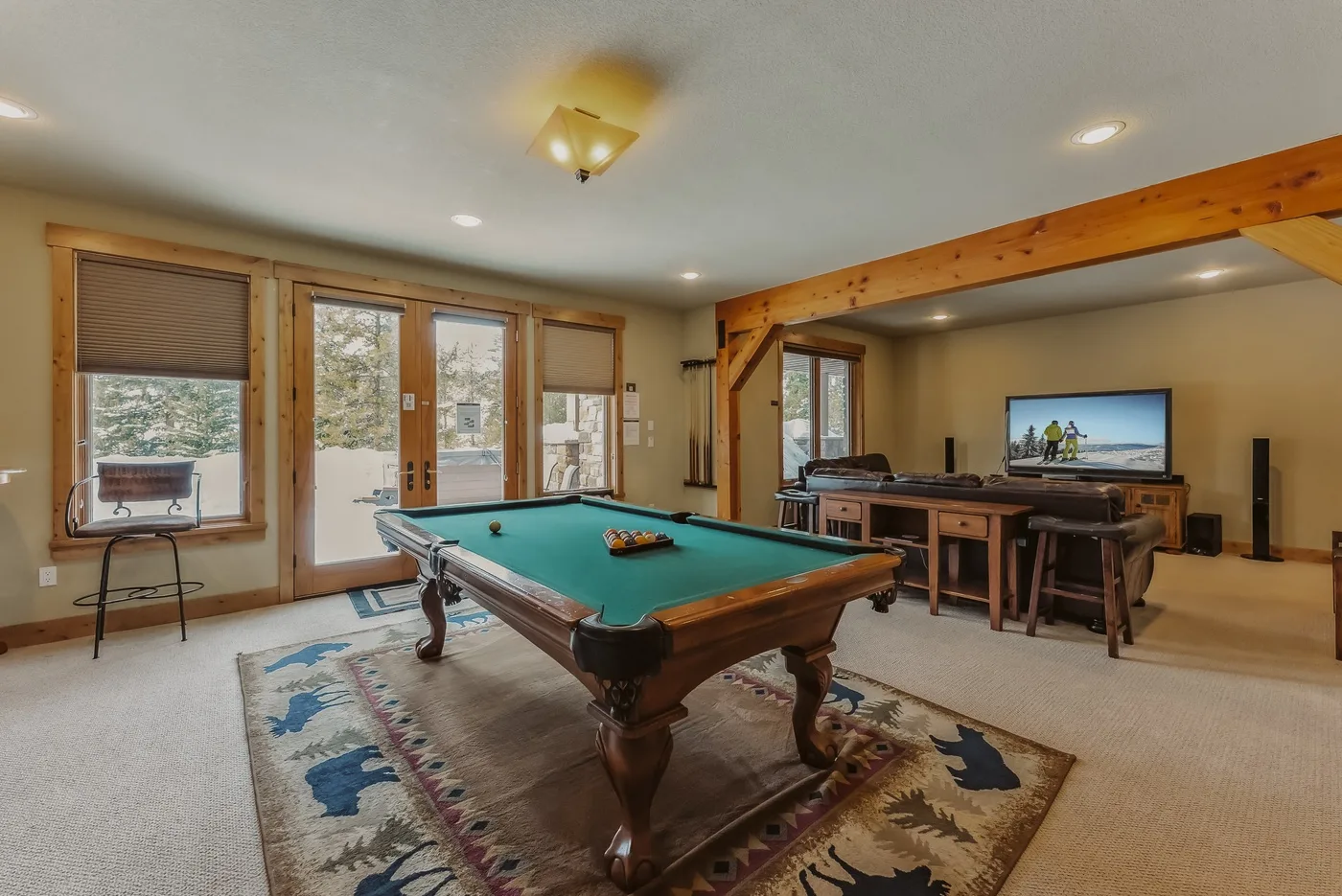 Una sala de juegos con una mesa de billar y una zona para sentarse junto a las ventanas.